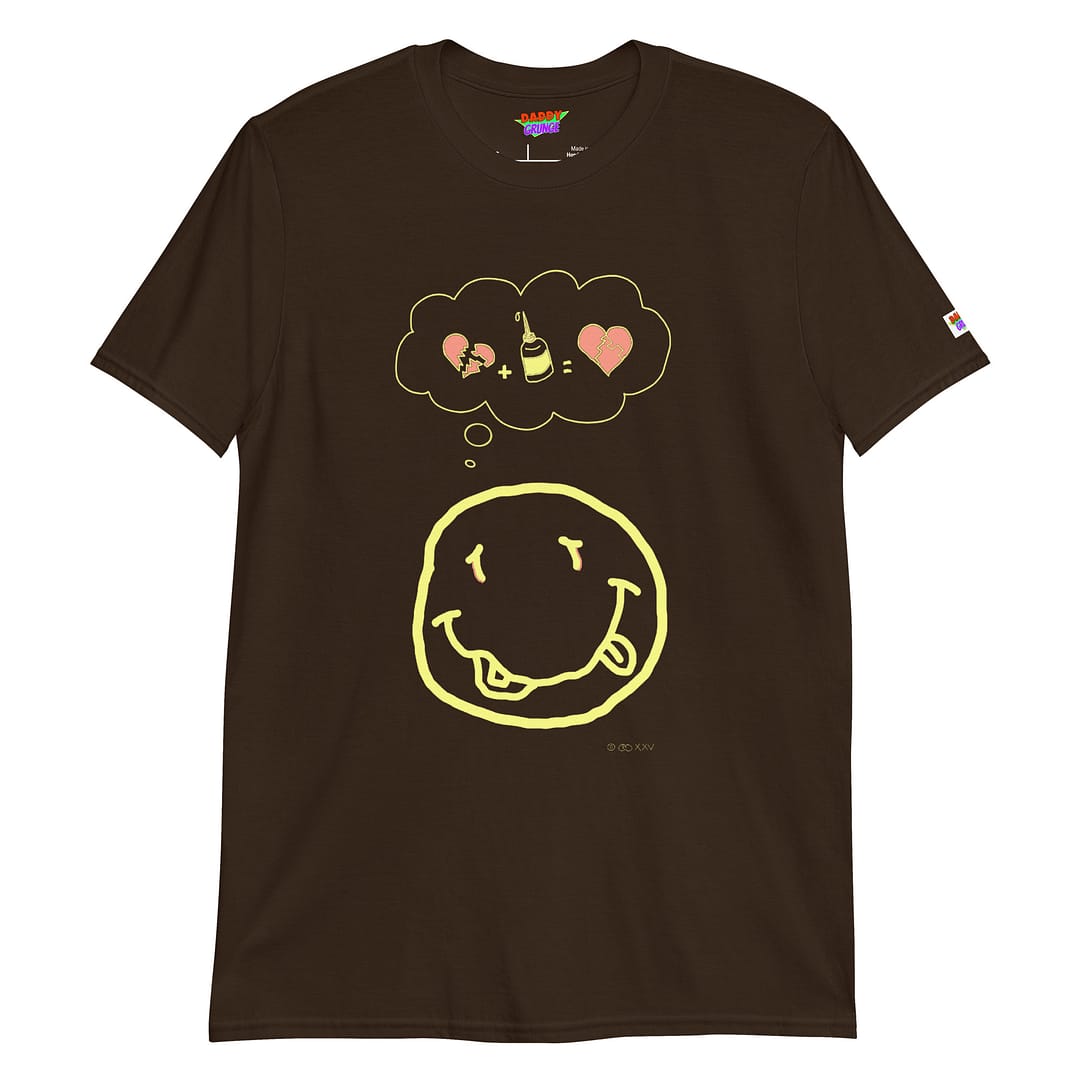 Picture with a dark brown colored shirt with a cartoonish yellow smiley resembling the Nirvana smiley who has a a thought bubble showing a broken heart with a glue squeeze bottle which connects the broken pieces to a repaired heart with the pieces glued together