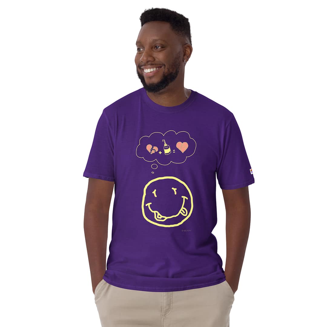 Smiling black guy looking to the right wearing a purple daddy grunge cartoon shirt with the altered Nirvana smiley and the thought bubble with the glued together heart pieces as a motive.